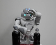 Nao robot places an effervescent antacid in a glass of water.